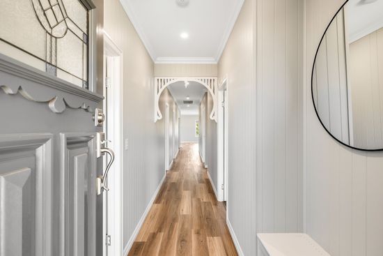 Long hallway with light wood floors, gray walls, white trim, and decorative archways.