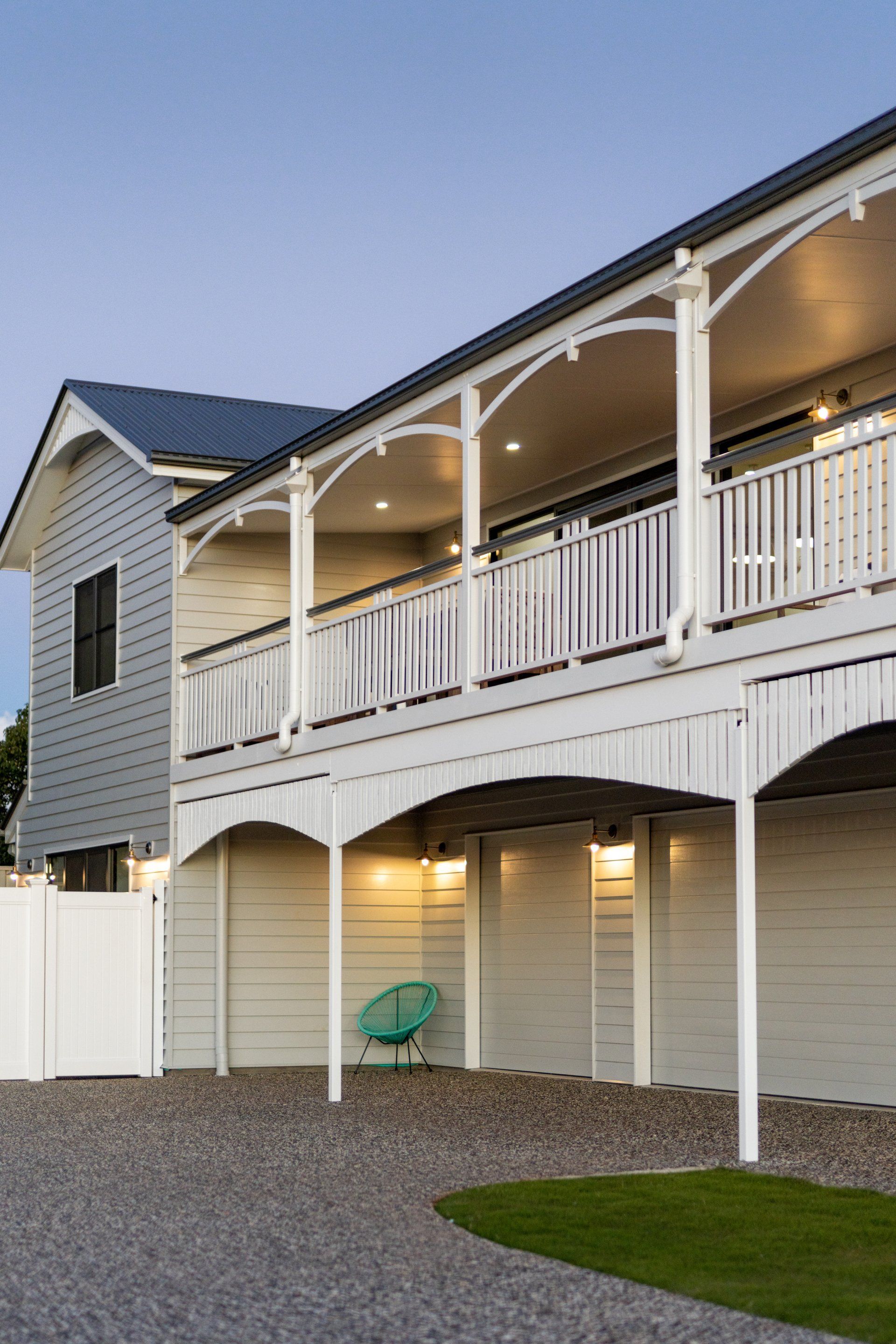 Two-story house with white trim, porch, and gray siding; a small lawn and gravel driveway are in front.