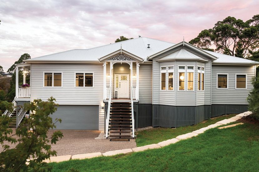 Light blue two-story house with a white roof, bay window, and wooden steps leading to the front door.
