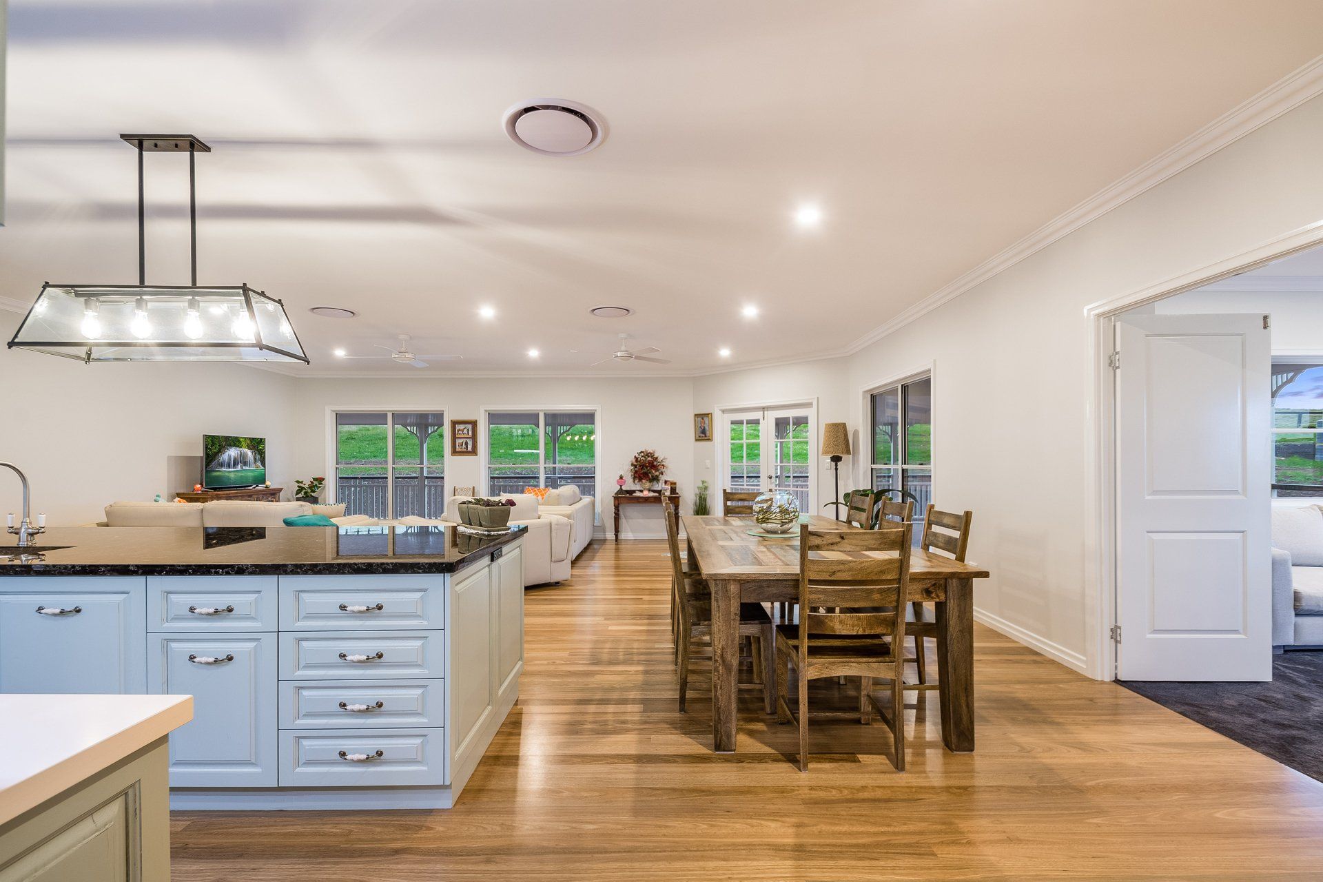 Open-plan kitchen and dining area with light blue cabinetry, wooden table, and hardwood floors.