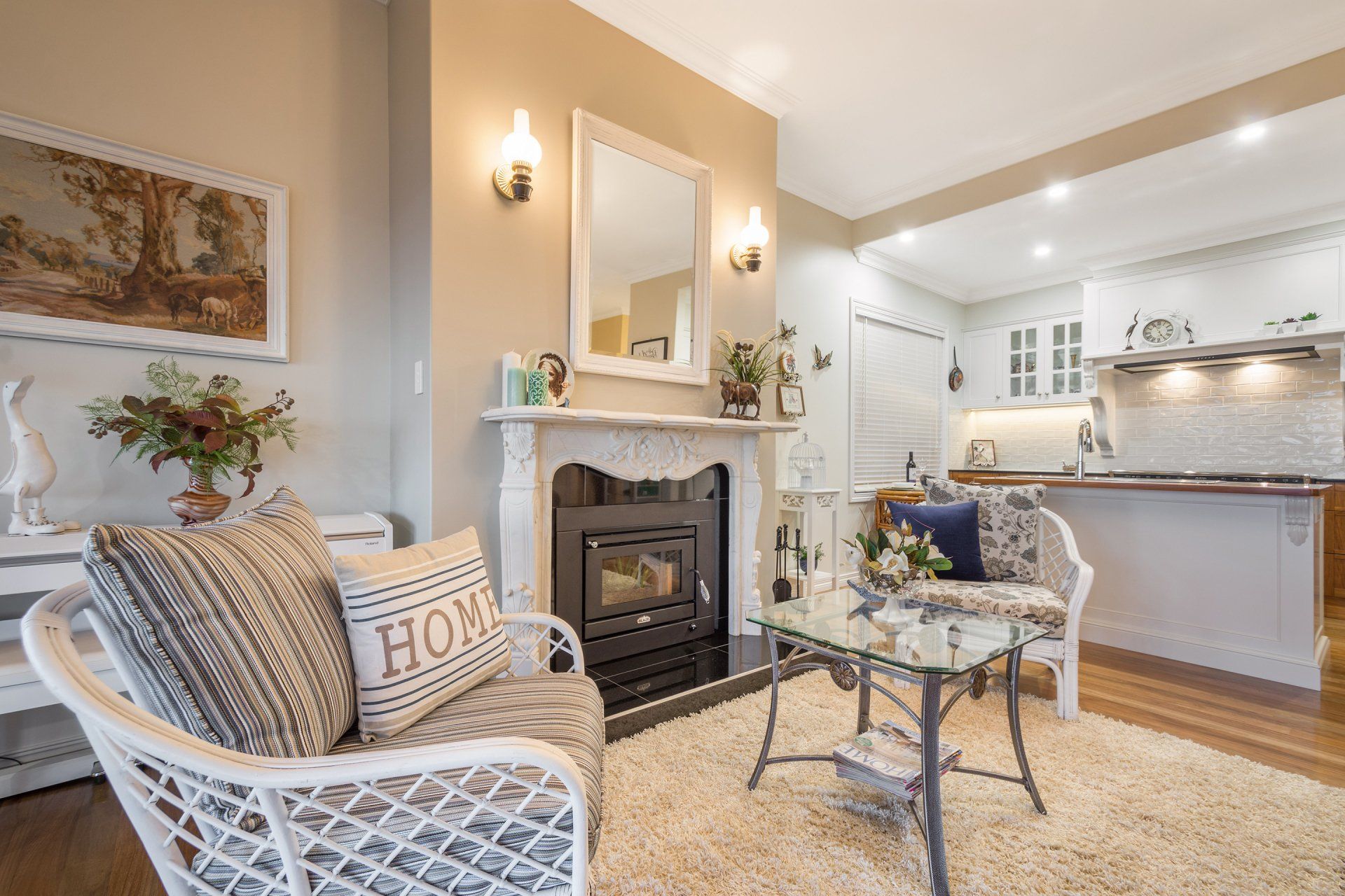 Cozy living room with fireplace, white wicker chairs, and open view to the kitchen.