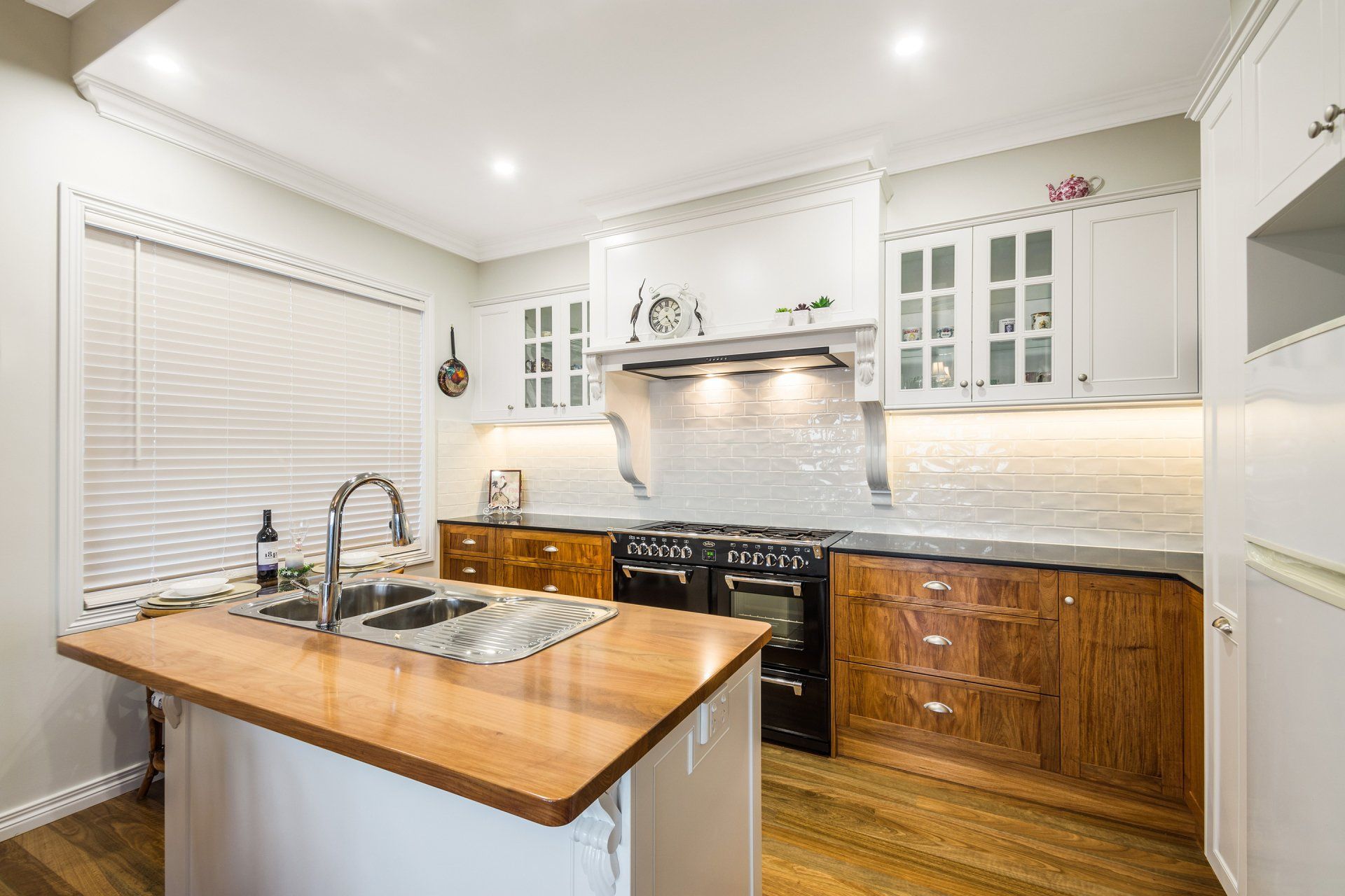 Kitchen with wooden island, countertops, and cabinets. Black stove, white walls, and bright lighting.