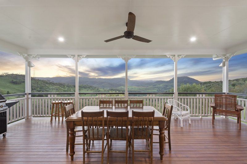 Covered porch with dining table and chairs, overlooking a scenic mountain view.