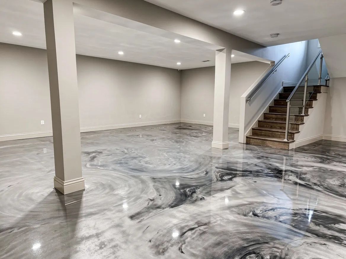 Empty basement with gray swirl-patterned floor and stairs on the right