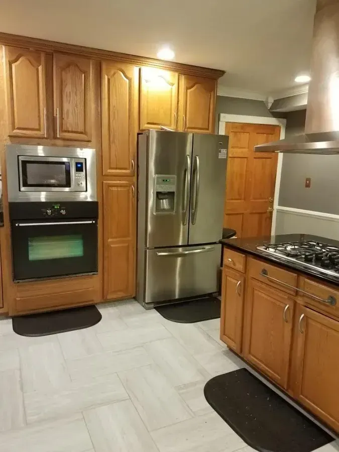 Modern kitchen with wooden cabinets, stainless steel fridge, microwave, oven, and gas range.