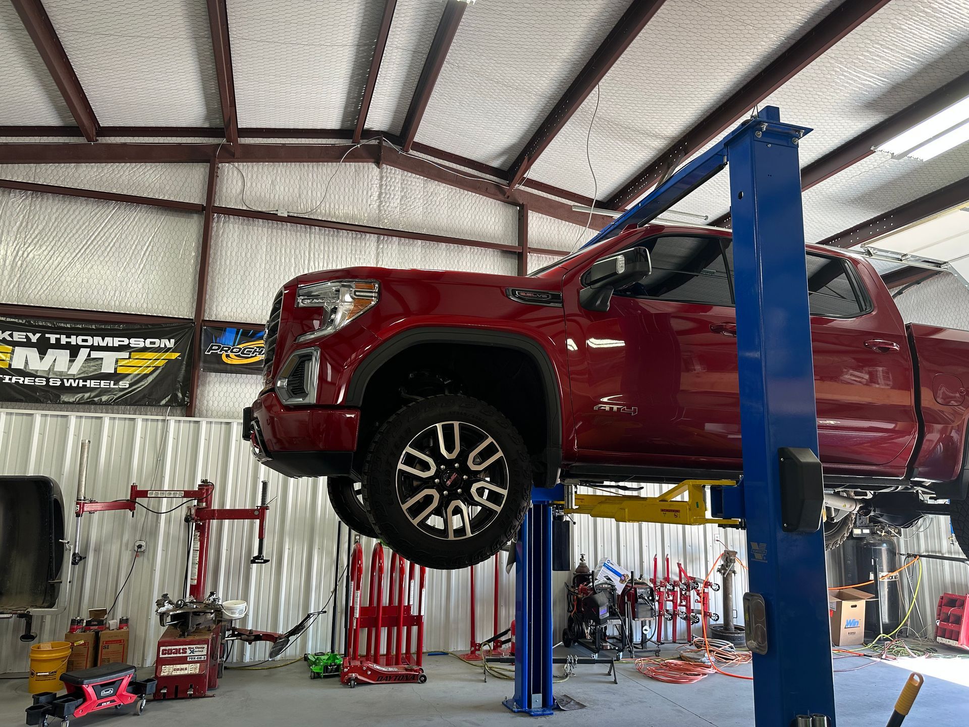 A red truck is sitting on a lift in a garage.