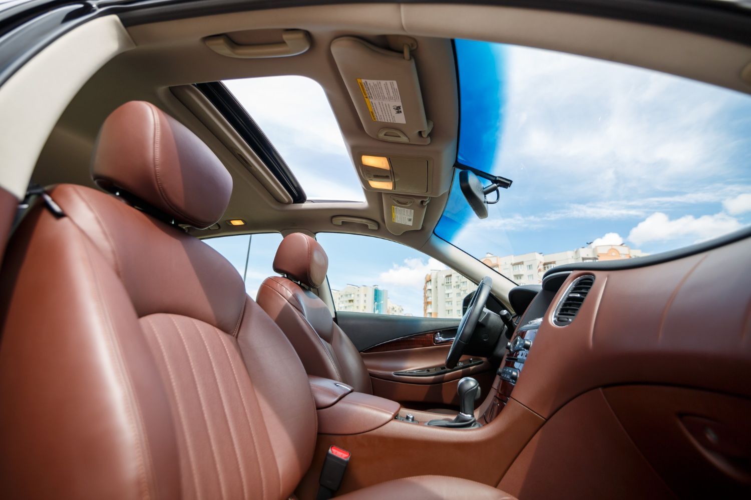 The inside of a car with brown leather seats and a sunroof.