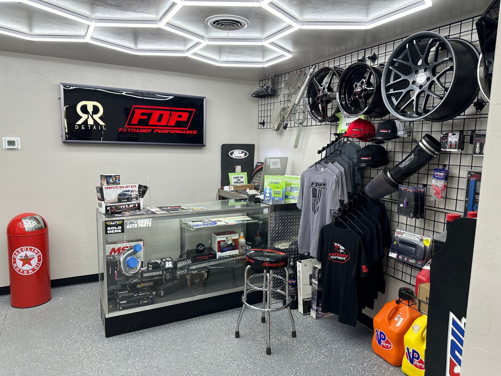 Auto parts store interior with wheels, shirts, and a display case.