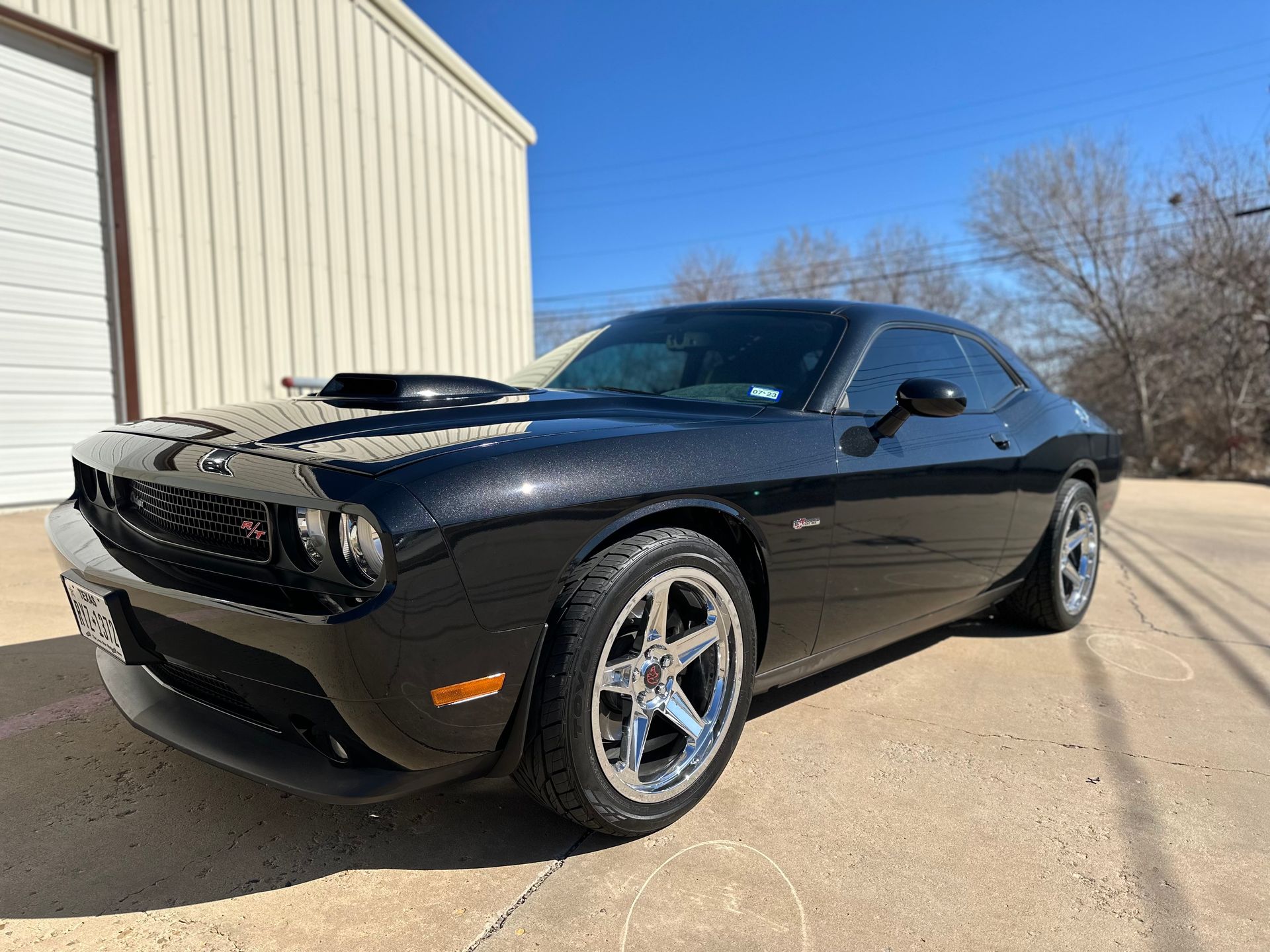 a black dodge challenger is parked in front of a garage .