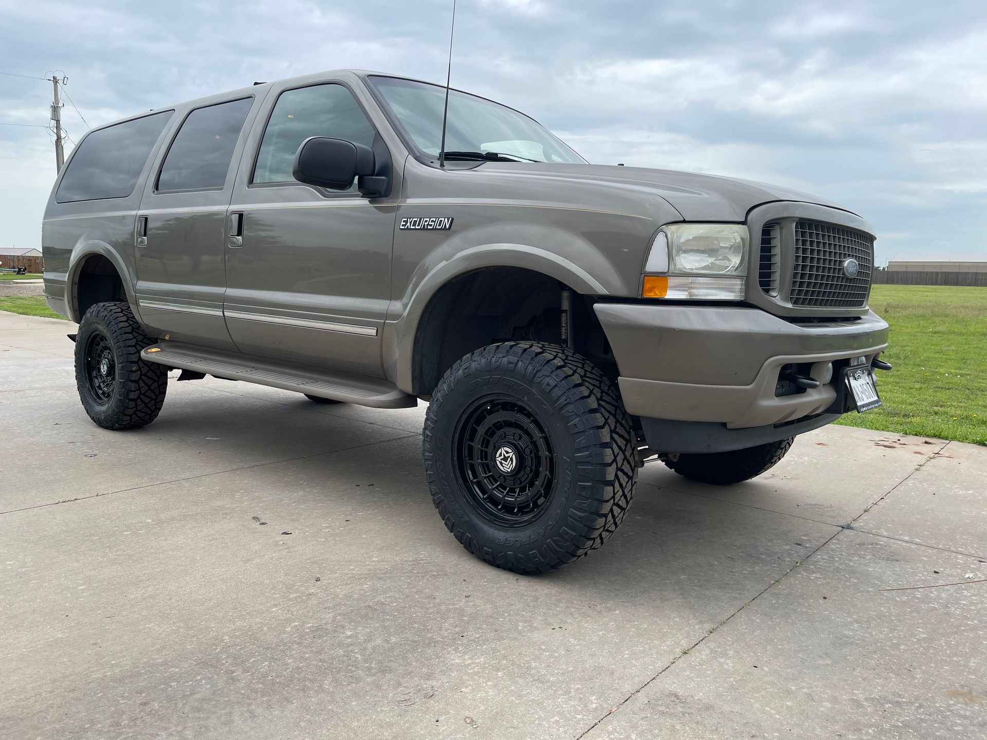 a ford excursion is parked on the side of a road .