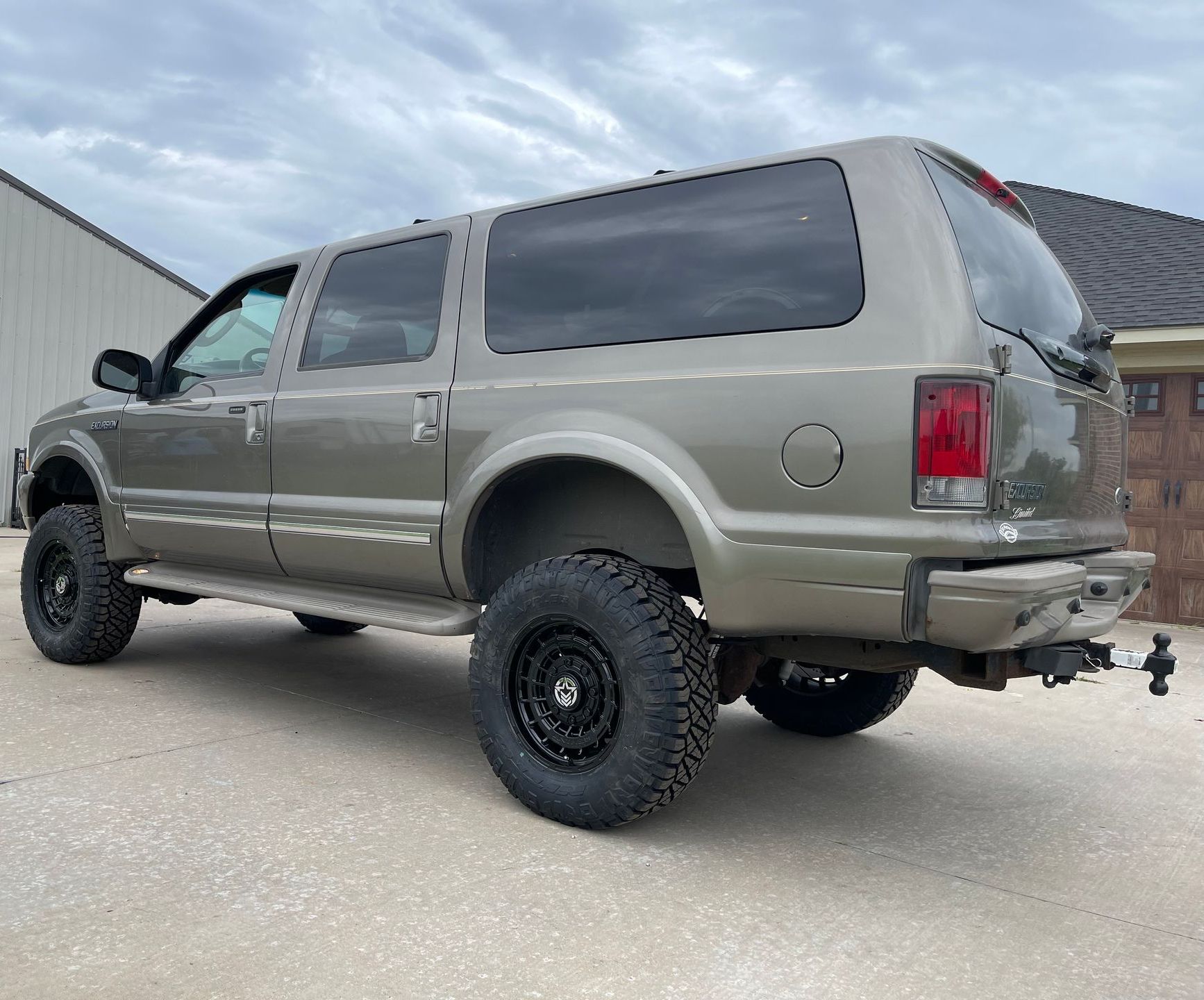 a ford excursion suv is parked in front of a house .