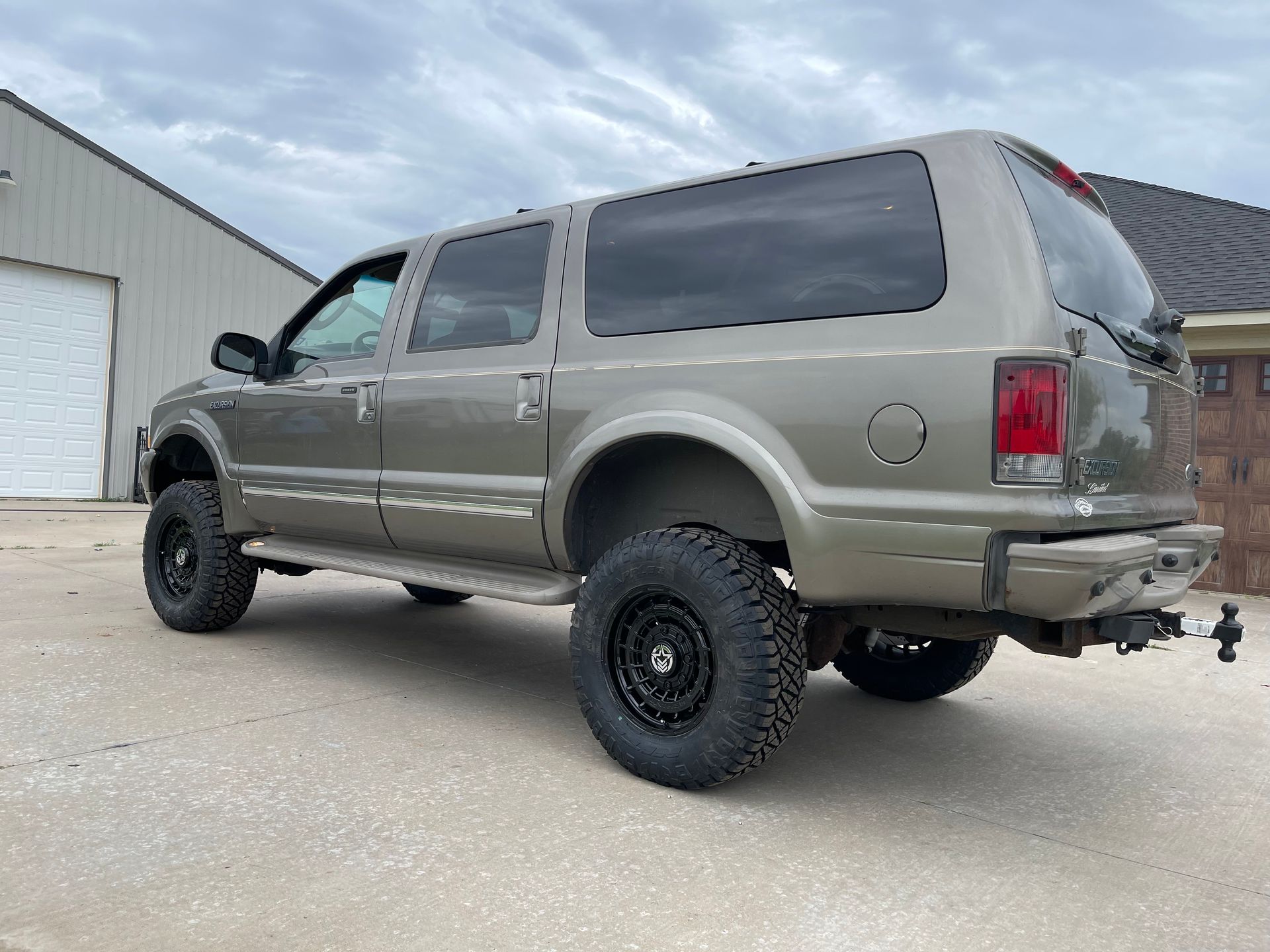 a ford excursion suv is parked in front of a garage .