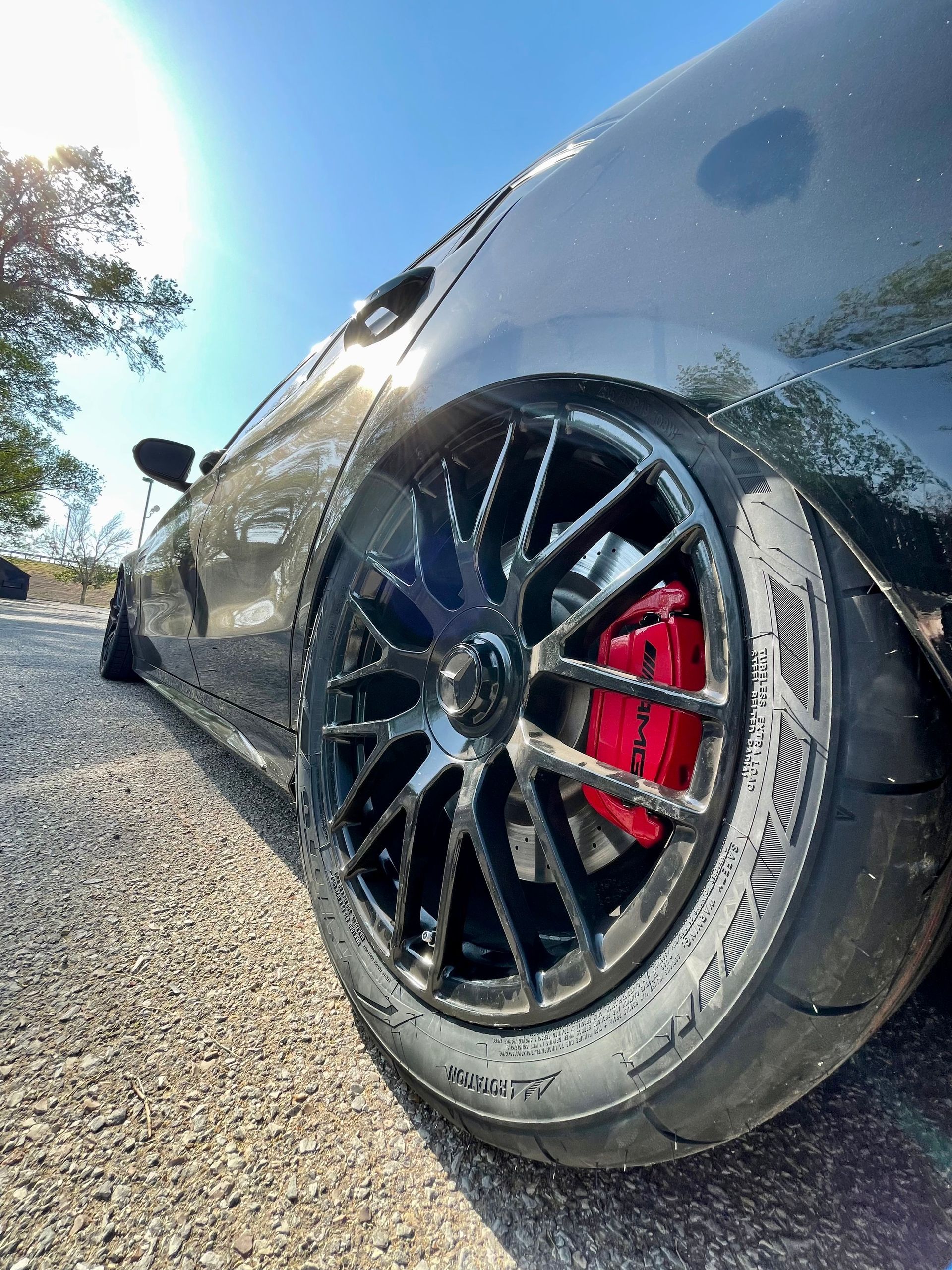 a black car with red brake calipers is parked on the side of the road .