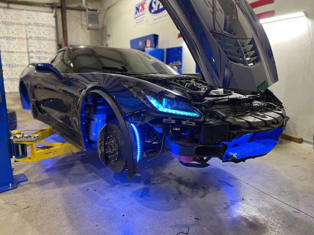 a black sports car with the hood open is on a lift in a garage .