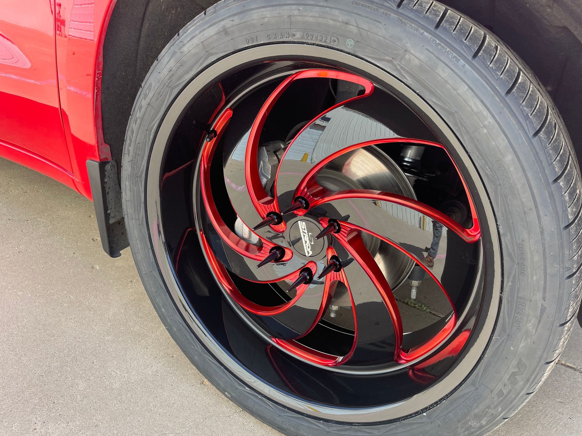 a close up of a red car wheel with a black tire