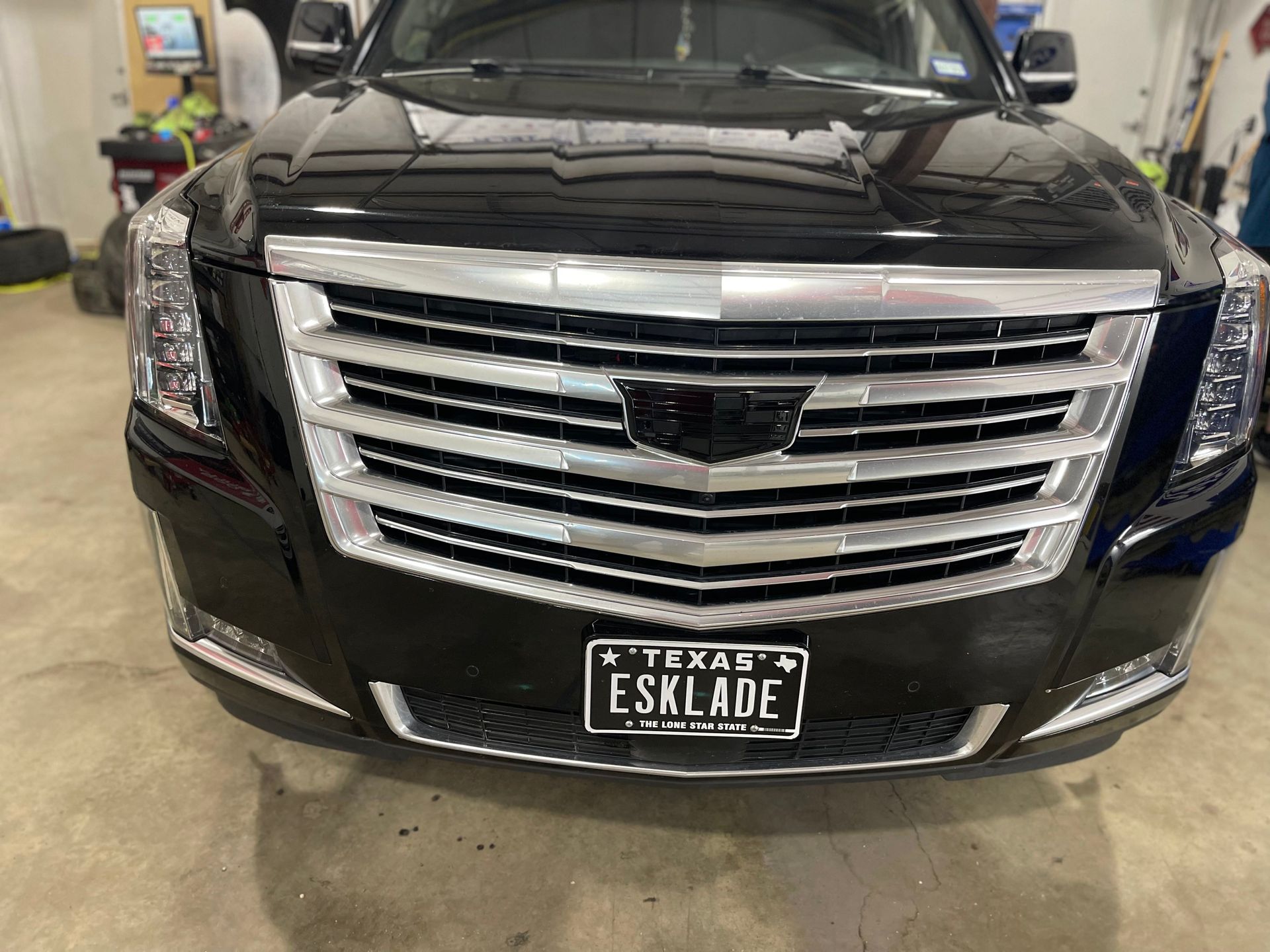 a black cadillac escalade with a texas license plate is parked in a garage .