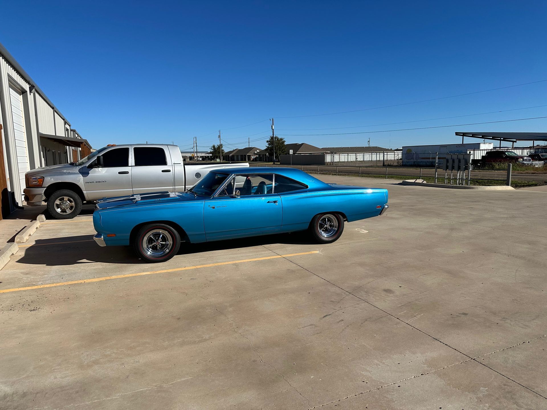 a blue car is parked next to a silver truck in a parking lot