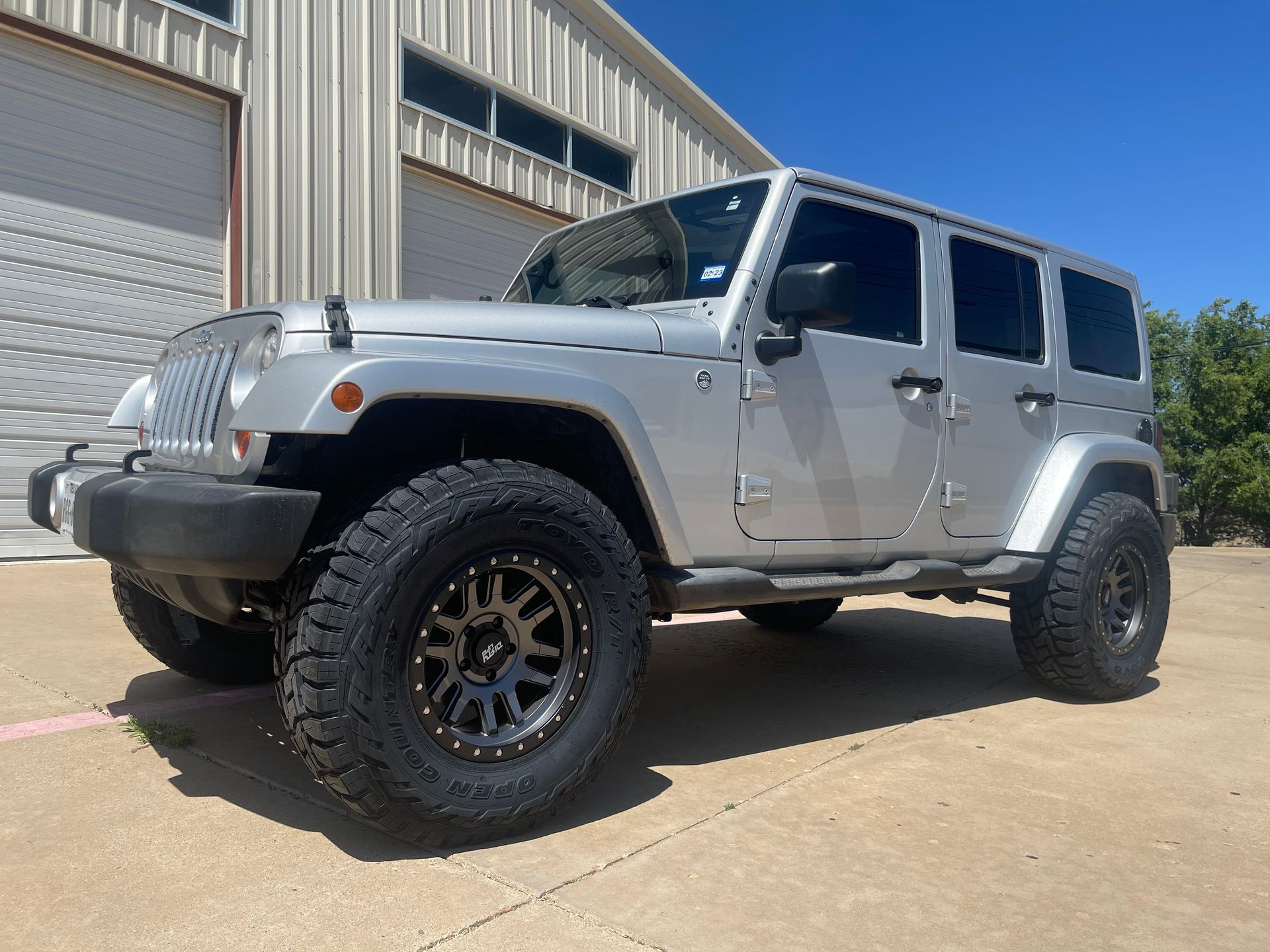a silver jeep is parked in front of a garage .