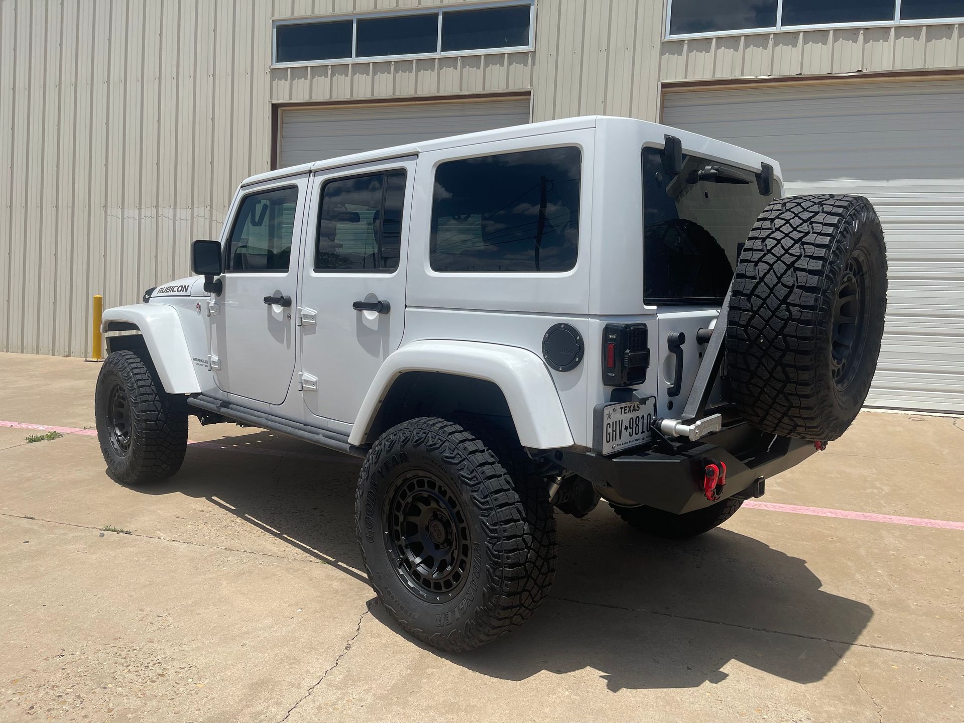a white jeep is parked in front of a garage door .