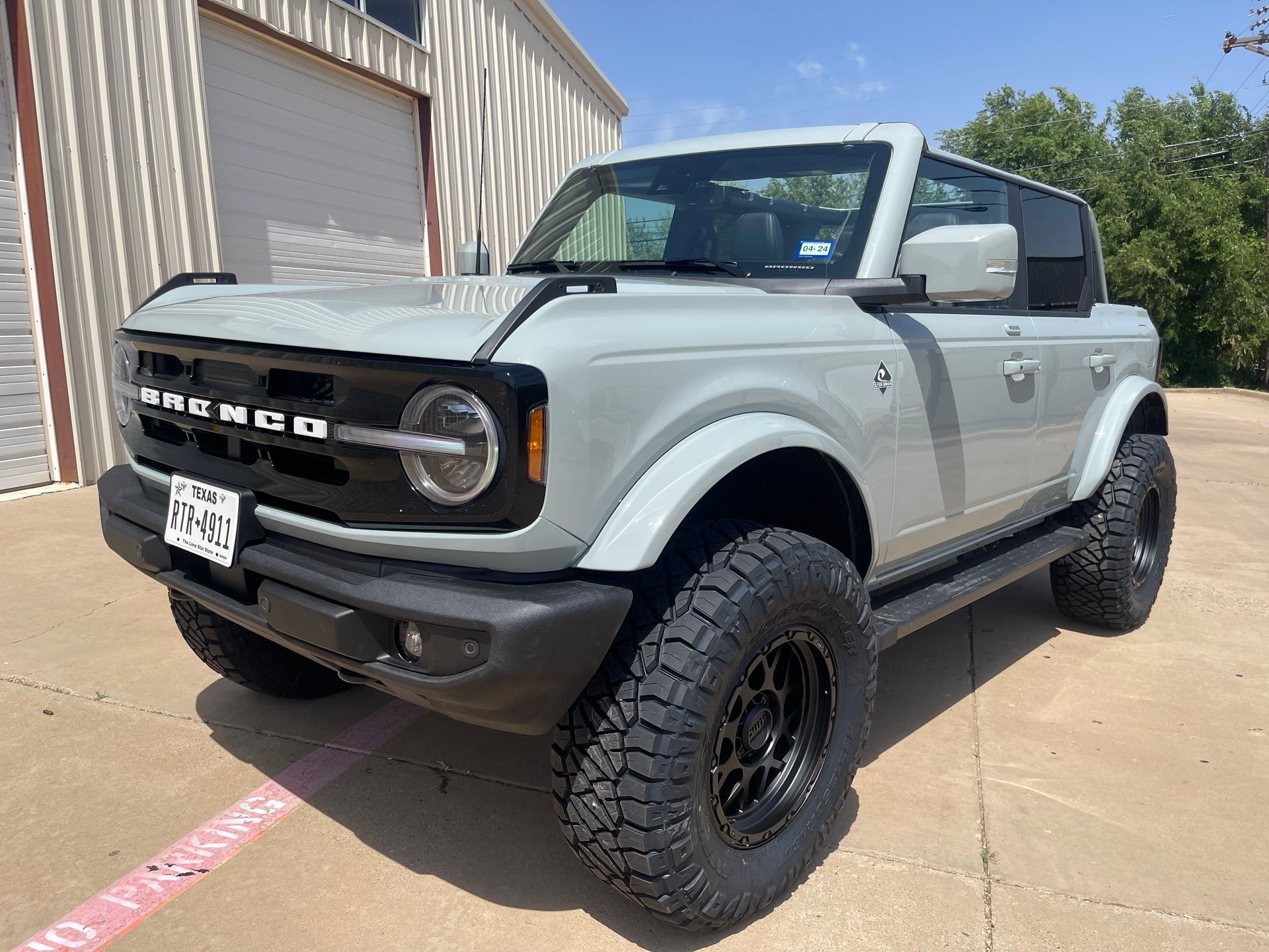 a white ford bronco is parked in front of a building .