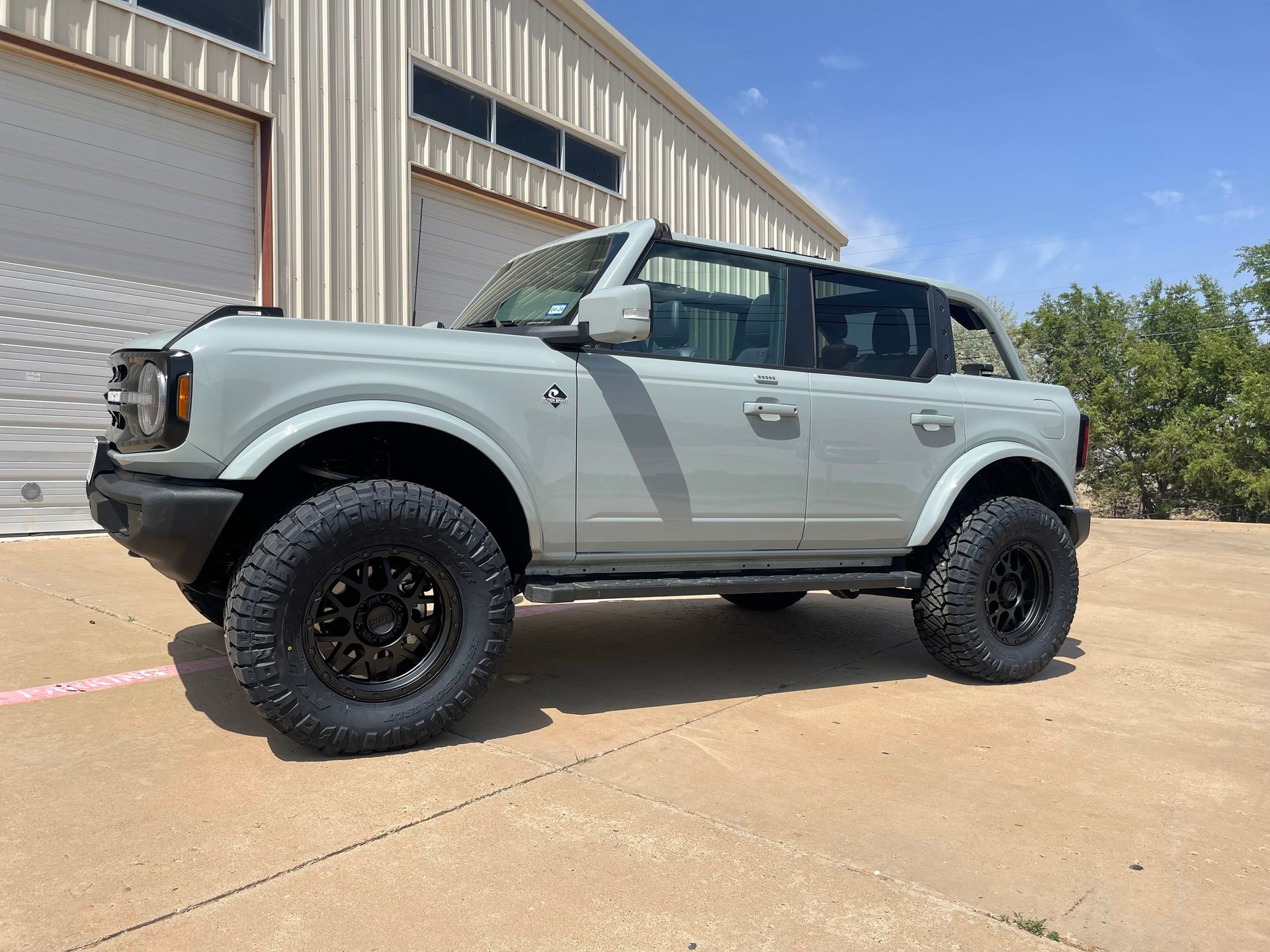a ford bronco is parked in front of a garage .