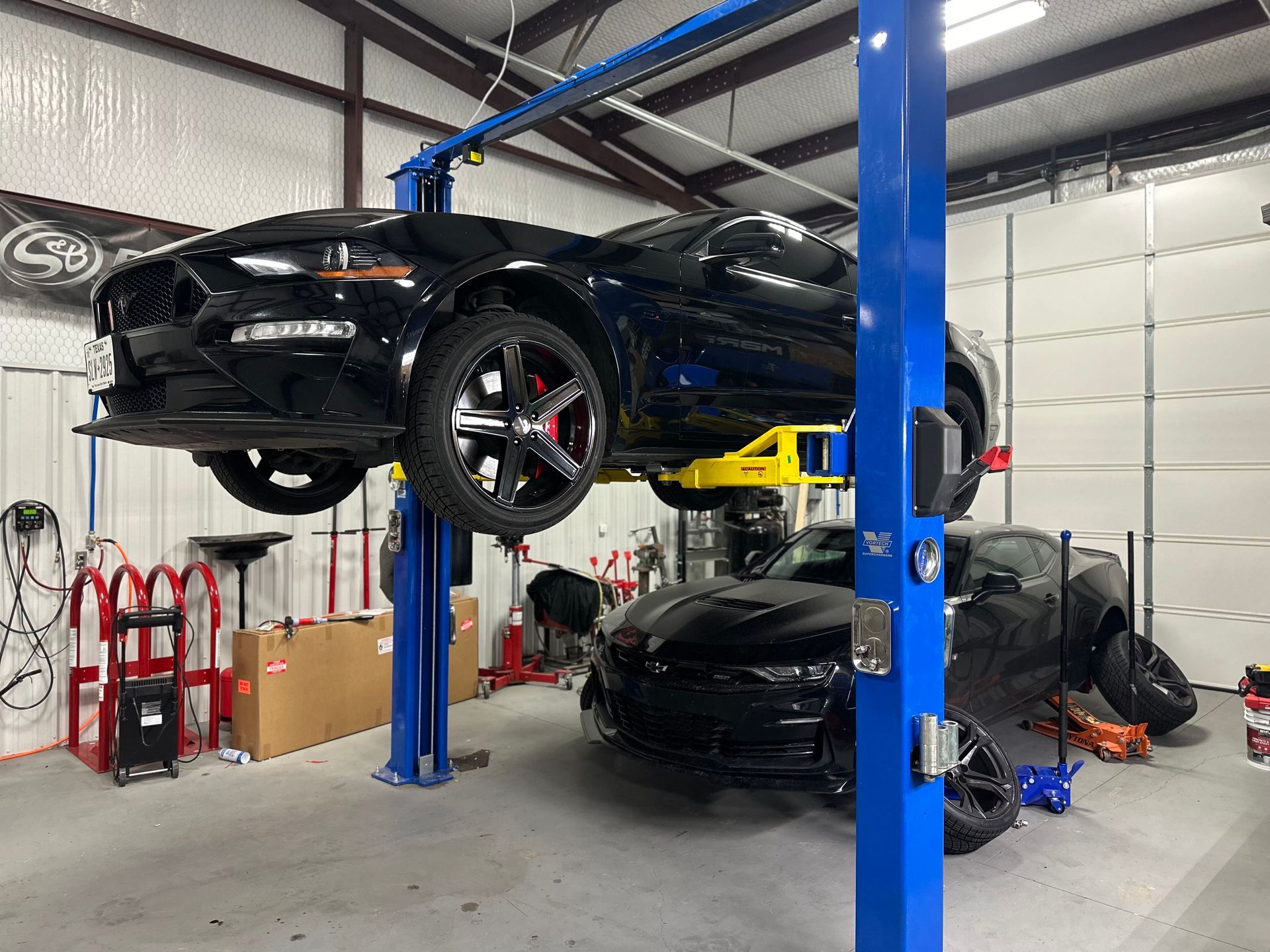 a black car is sitting on top of a blue lift in a garage .