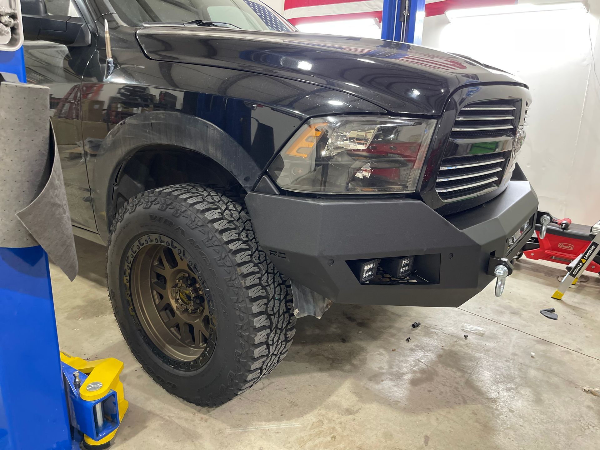 a black truck is parked in a garage next to a lift .