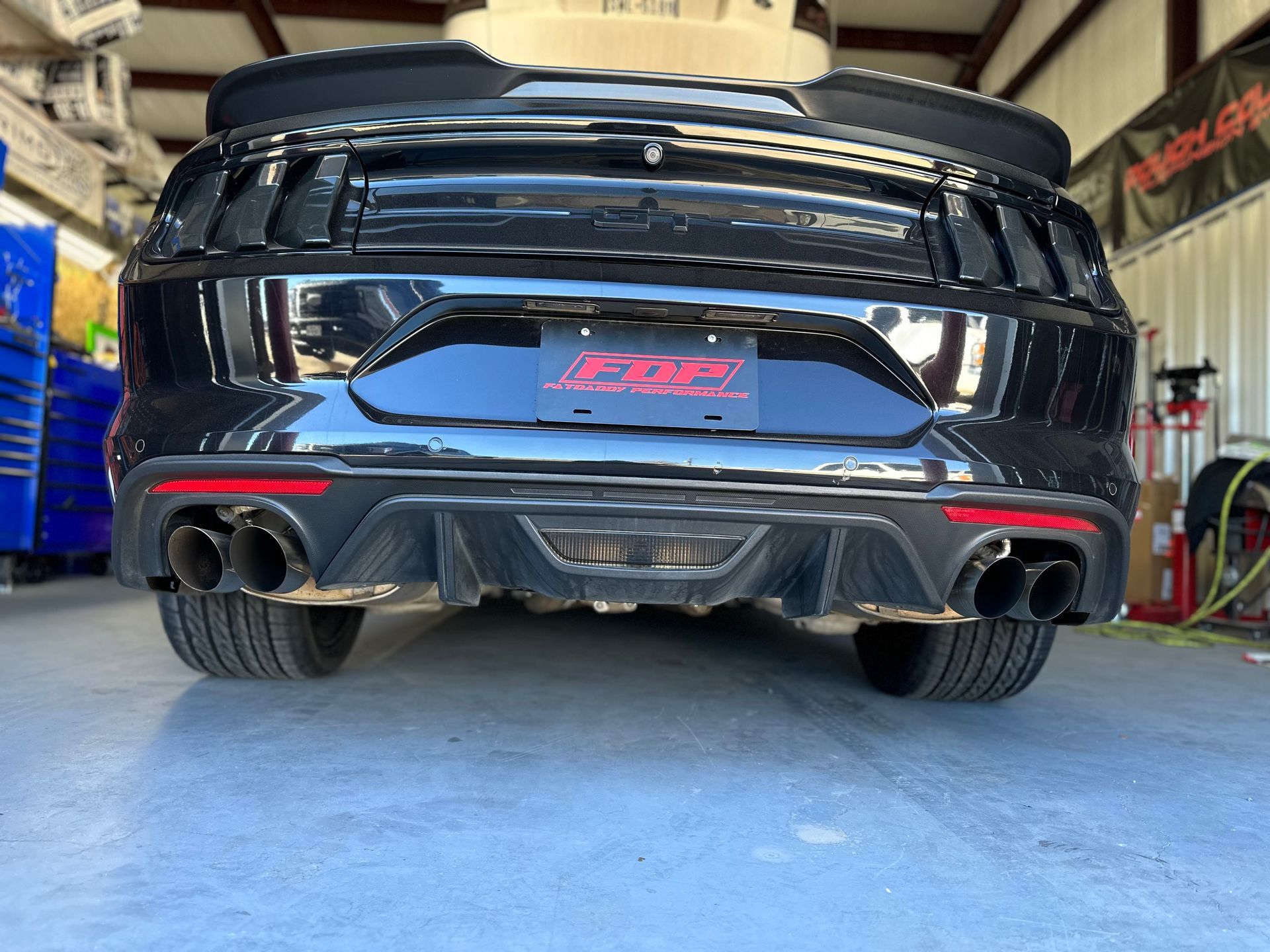 a black ford mustang is parked in a garage .