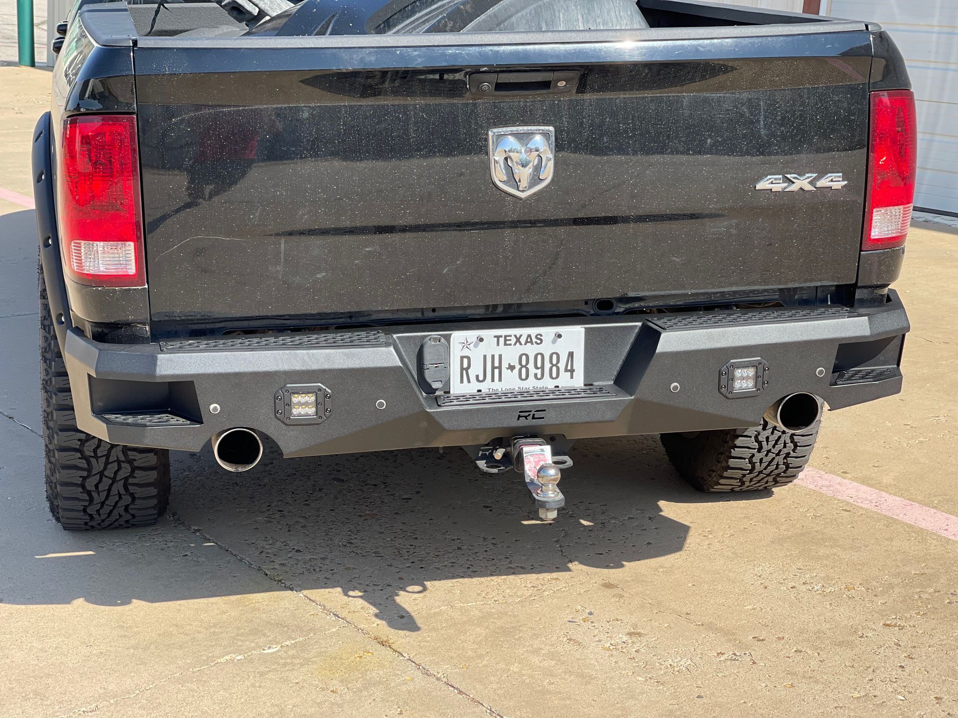 a black truck with a license plate that says pjh-199fc is parked on the side of the road .