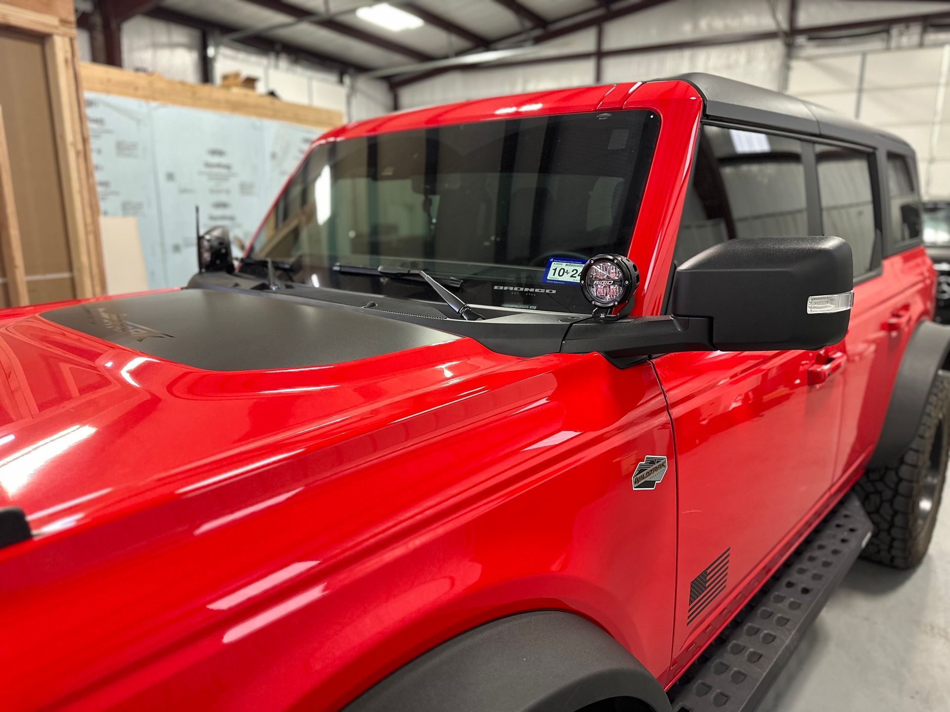 a red ford bronco is parked in a garage .