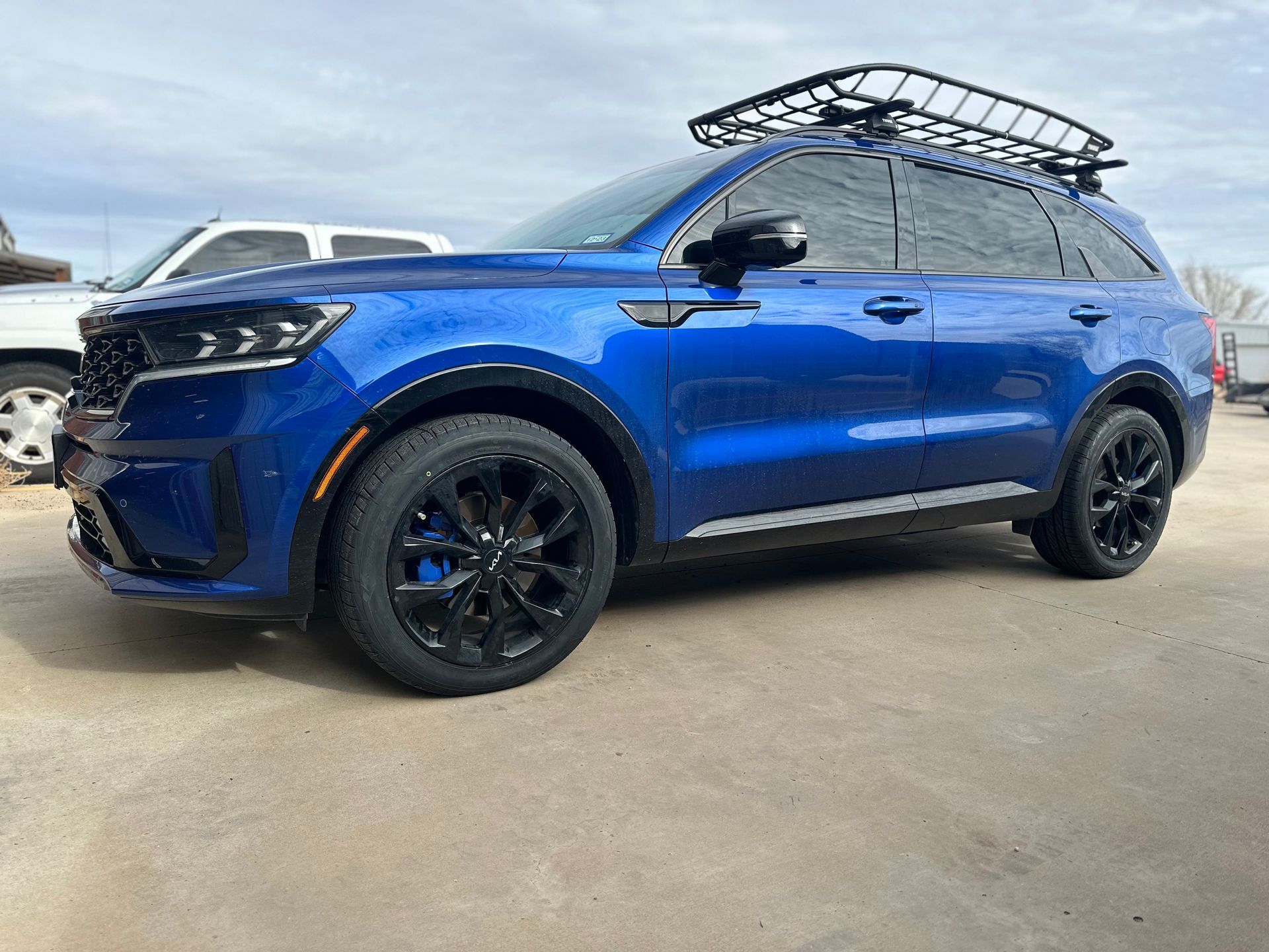 a blue suv with a roof rack on top of it is parked in a parking lot .
