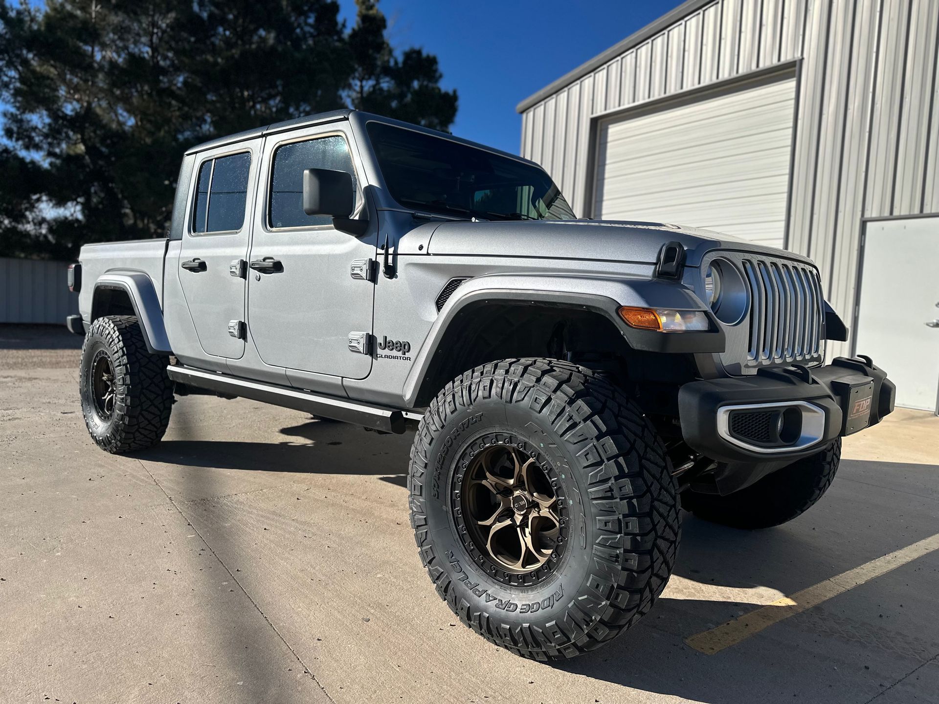 a silver jeep gladiator is parked in front of a garage .