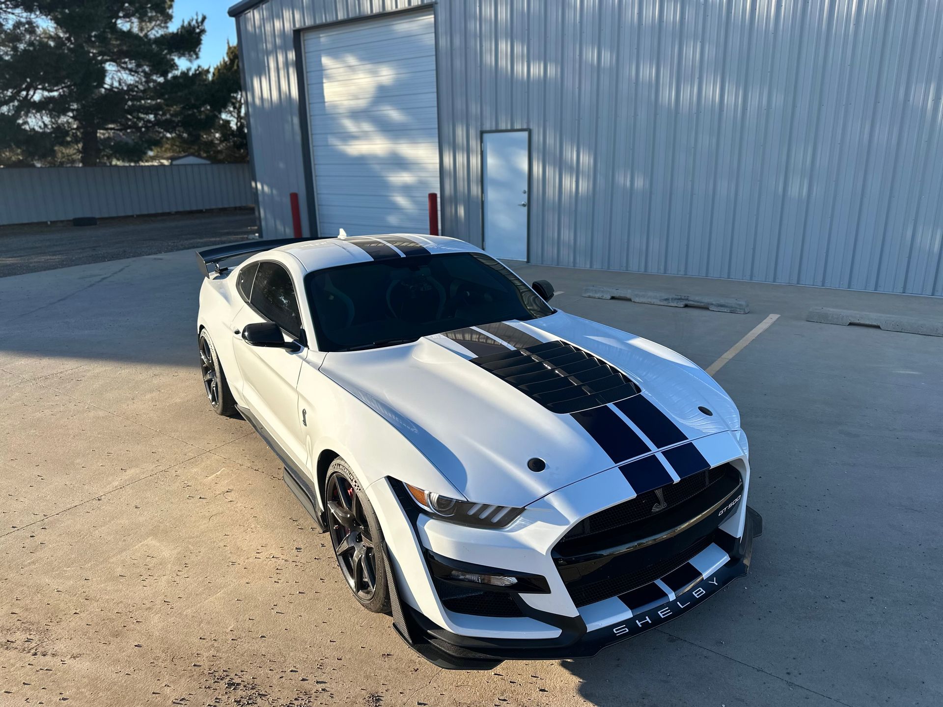 a white ford mustang is parked in a parking lot in front of a building .