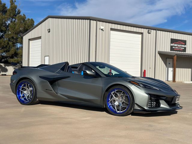 a gray sports car with blue wheels is parked in front of a building .