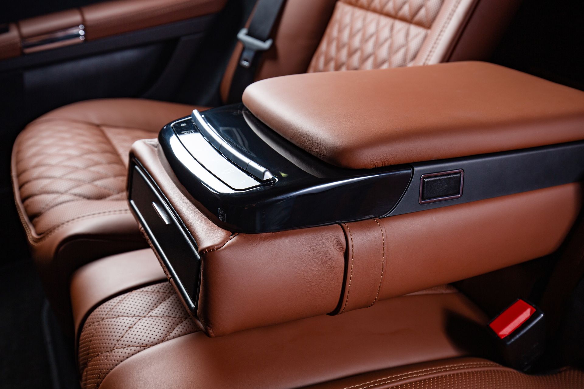 a brown leather arm rest in the back seat of a car .