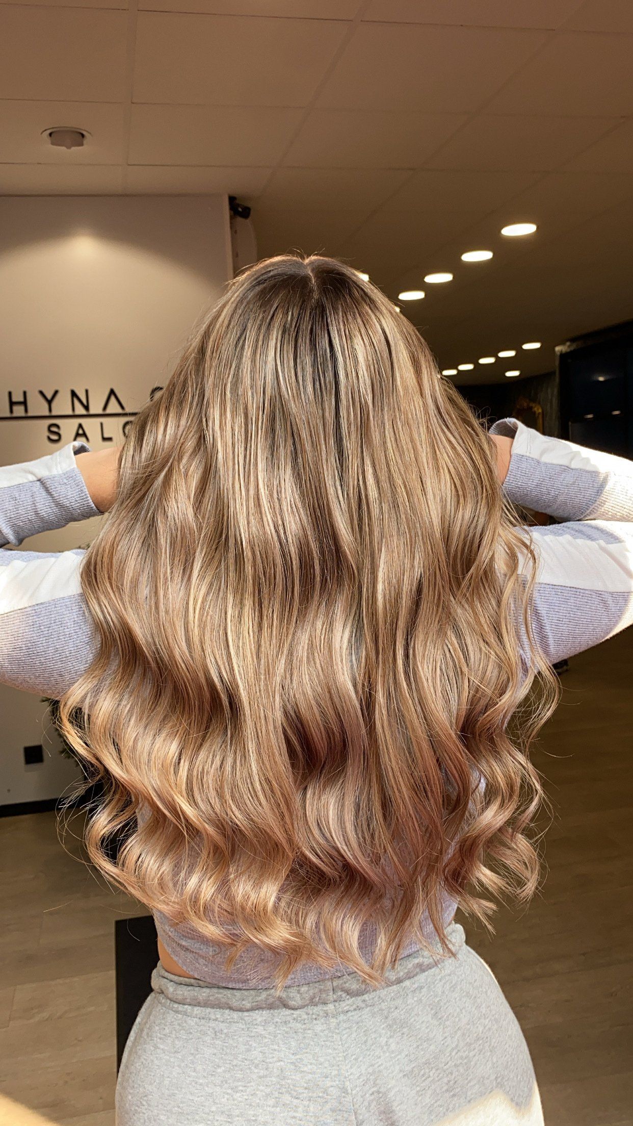 Eine Frau mit langen blonden Haaren steht mit ausgestreckten Armen in einem Raum.