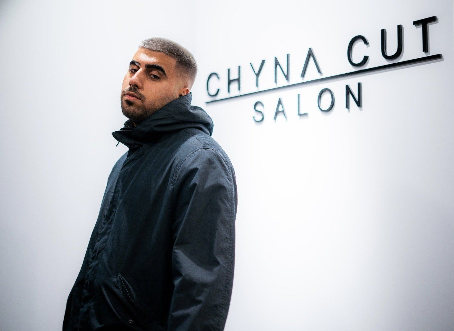 Ein Mann steht vor einem Schild mit der Aufschrift „Chyna Cut Salon“