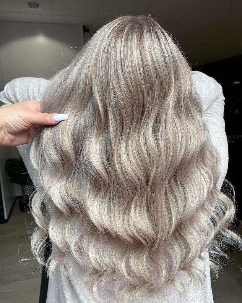 Eine Frau mit langen blonden Haaren lässt sich von einem Friseur die Haare machen.