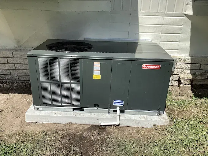 Gray Goodman air conditioner unit on a concrete pad next to a building.