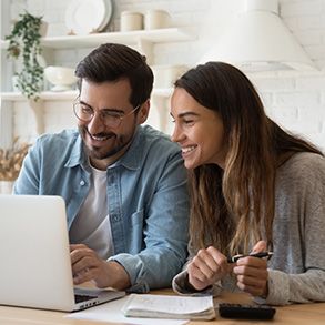 Woman with glasses holding credit card, using a laptop, smiling.