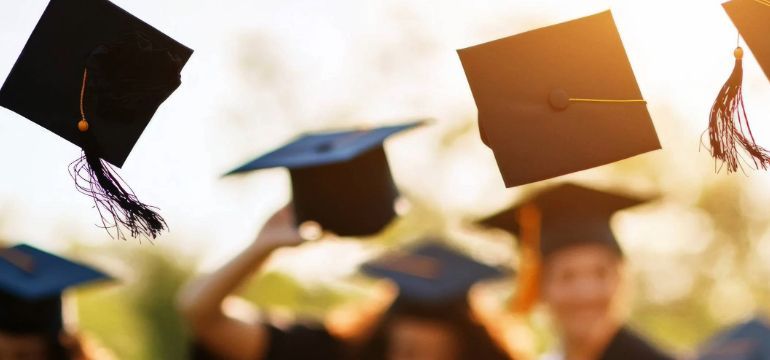 Graduates toss their caps into the air at a graduation ceremony, ERMU is promoting it scholarships.