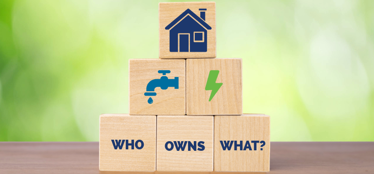 Stacked wooden blocks with house, water, and electricity icons above the text ‘Who Owns What?