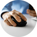 Person's hand on a black computer mouse, resting on a white surface. The person wears a blue shirt.
