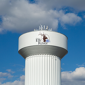 Water tower in Elk River, Minnesota, with the city's logo featuring an elk, under a cloudy sky.