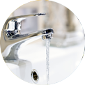 Chrome faucet with water running into a white sink.