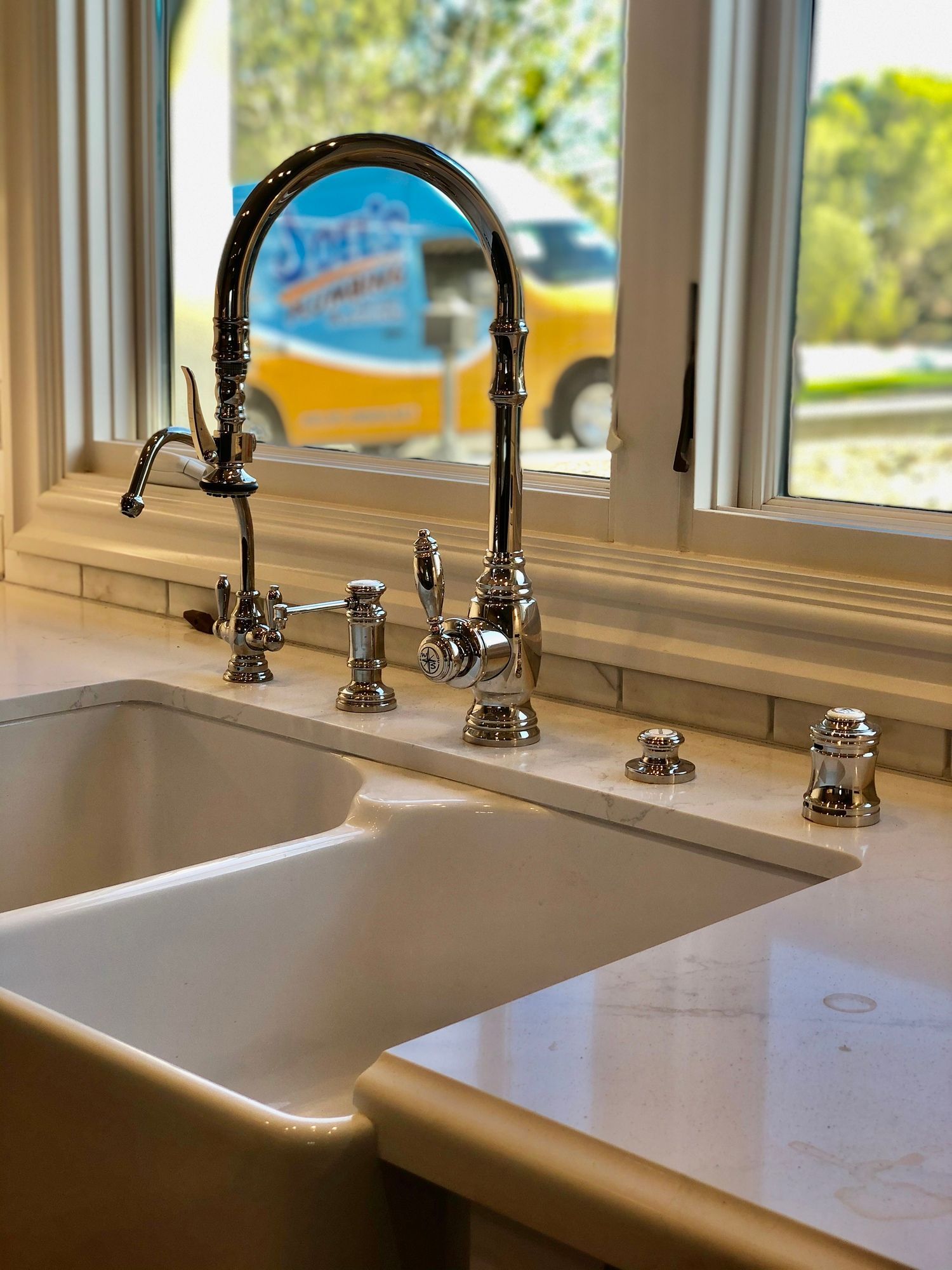 A kitchen sink with a faucet and a window in the background