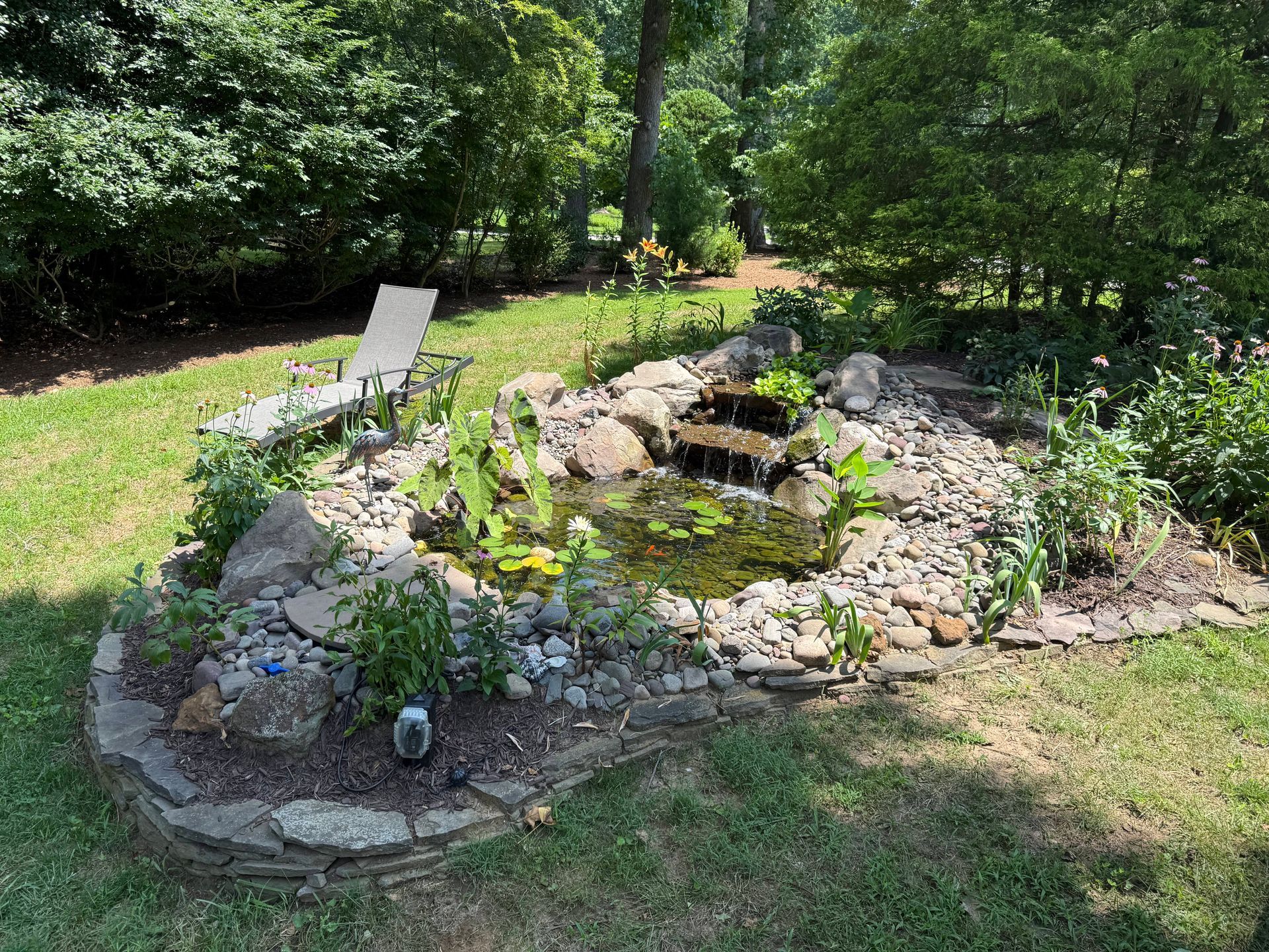 A person laying sod in a garden bed with colorful plants and stones, aerial view.