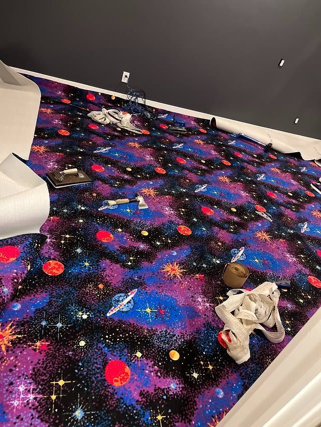 Colorful galaxy-pattern carpet in a room with a white chair and scattered items on the floor
