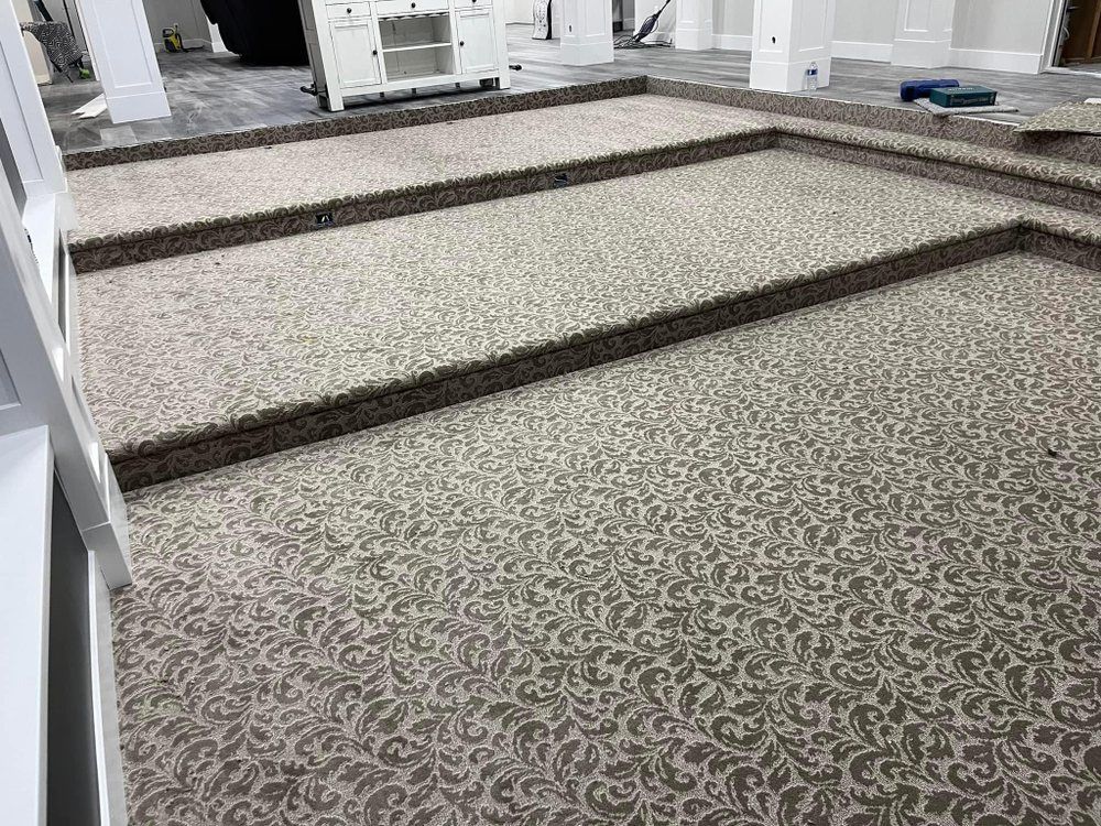 Patterned carpeted steps in a bright indoor space, with dark wooden edges and white railings.