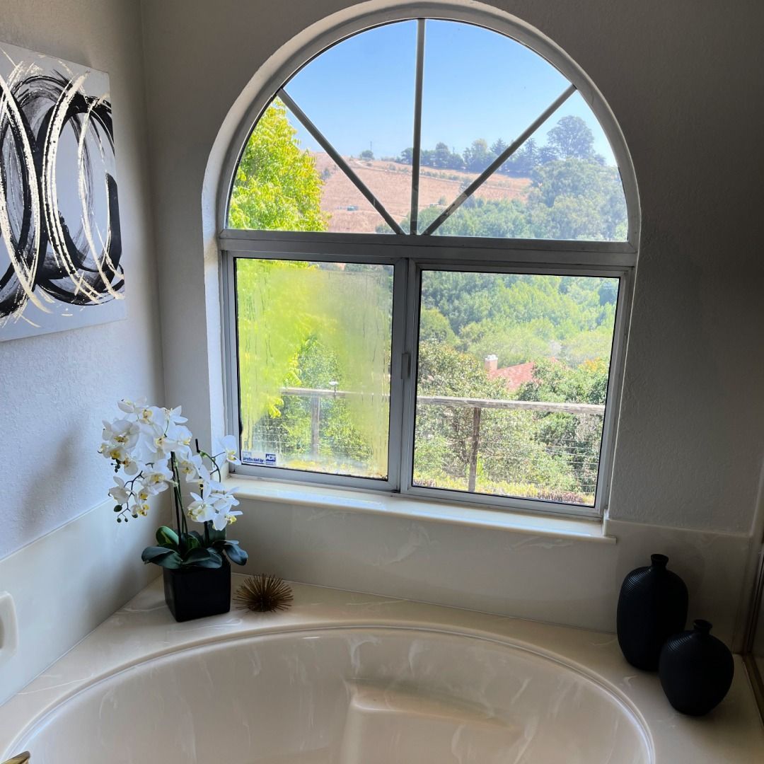 A bathtub in front of a window with a view of trees